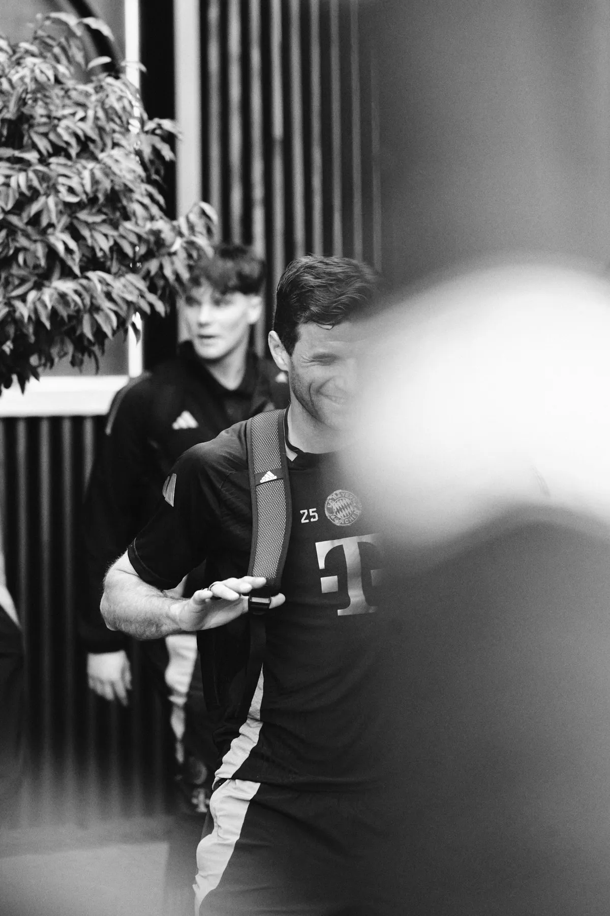 Bundesliga, lächelnder Spieler im Trainingsshirt auf dem Weg durch den Spielertunnel, unscharfer Vordergrund, Schwarzweiß, Sportfotografie, fotografiert von Kilian Amrehn