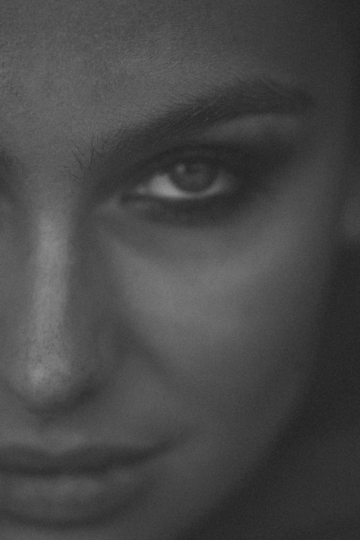 Marie, Nahaufnahme mit Blick über die Schulter und leichtem Lächeln, Gesicht halb im Schatten, schwarzweiß, 2022, fotografiert von Kilian Amrehn