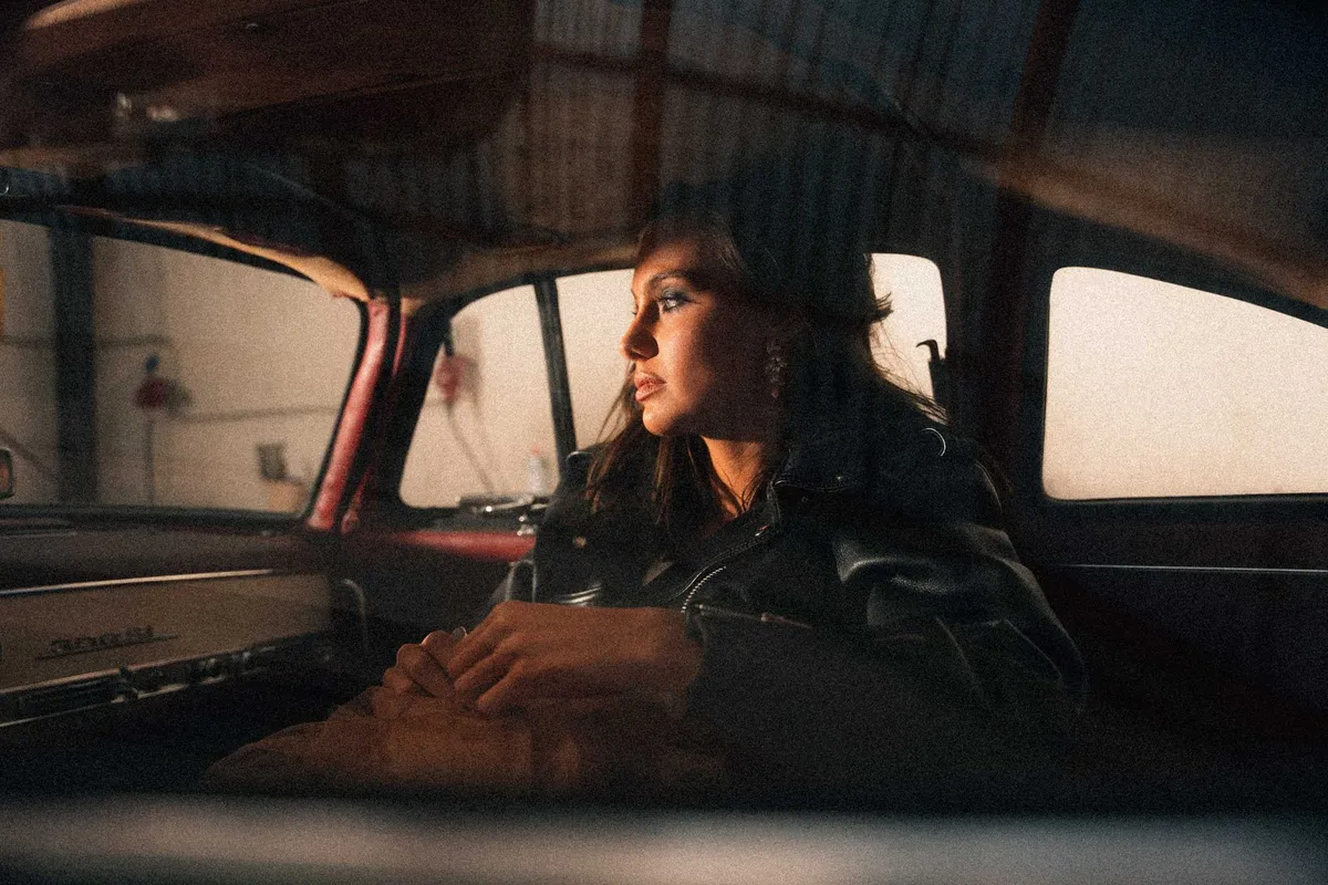 Marie, Frau in Lederjacke sitzt im Oldtimer und blickt aus dem Fenster, warmes Abendlicht, Porträtserie 2022, fotografiert von Kilian Amrehn