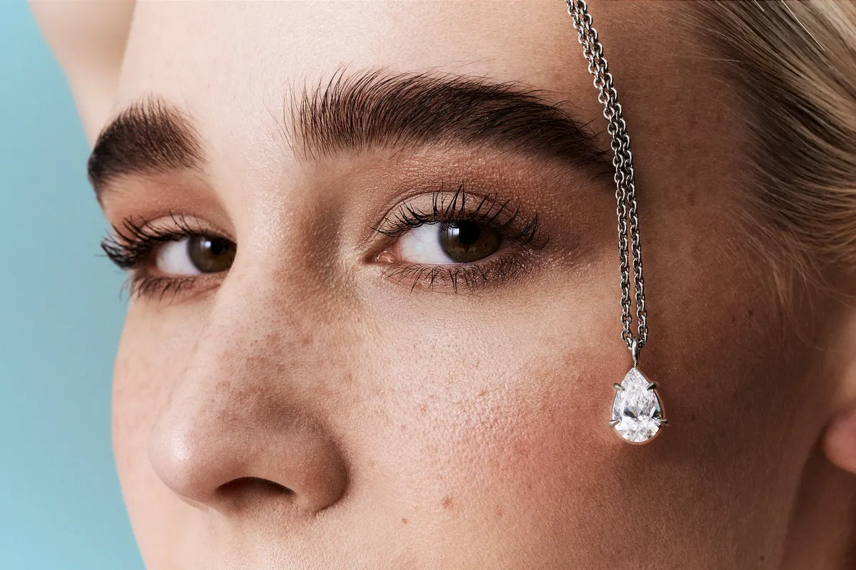 Monano, Kette mit tropfenförmigem Diamantanhänger hängt vor dem Gesicht eines Models mit Sommersprossen, Schmuckkampagne 2024, fotografiert von Kilian Amrehn