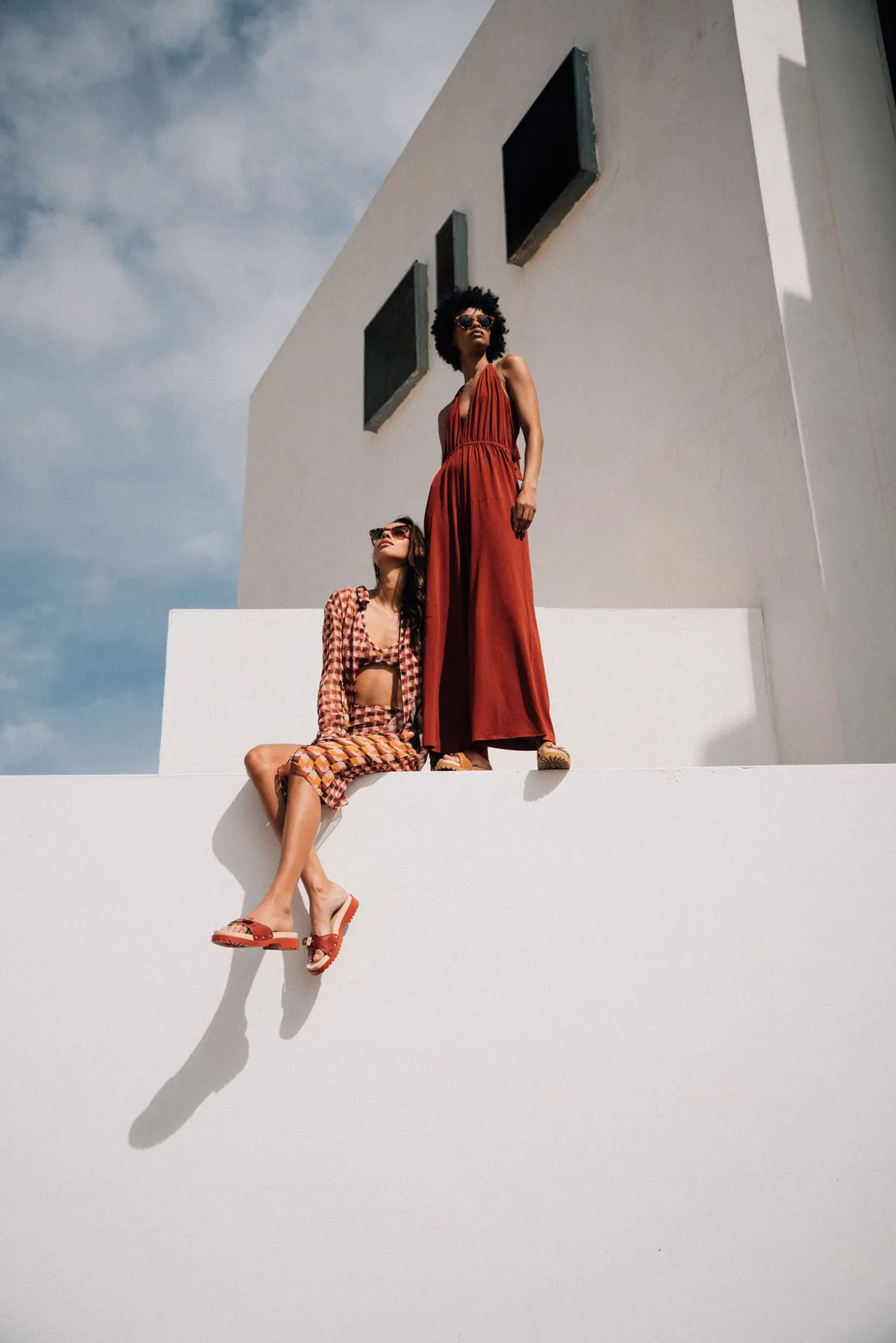 Scholl iconic, zwei Models in Rot und Terrakotta mit Sandalen auf weißer Architektur vor Himmel, Kampagne Fuerteventura 2021, fotografiert von Kilian Amrehn